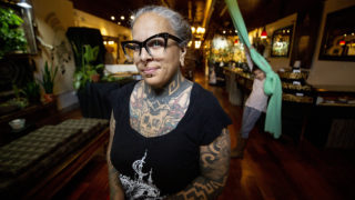Alicia Cardenas, owner of Sol Tribe Tattoo and Body Piercing, stands in her Broadway shop as her kid, Xochitl, plays on a silk behind her. April 22, 2020. (Kevin J. Beaty/Denverite)