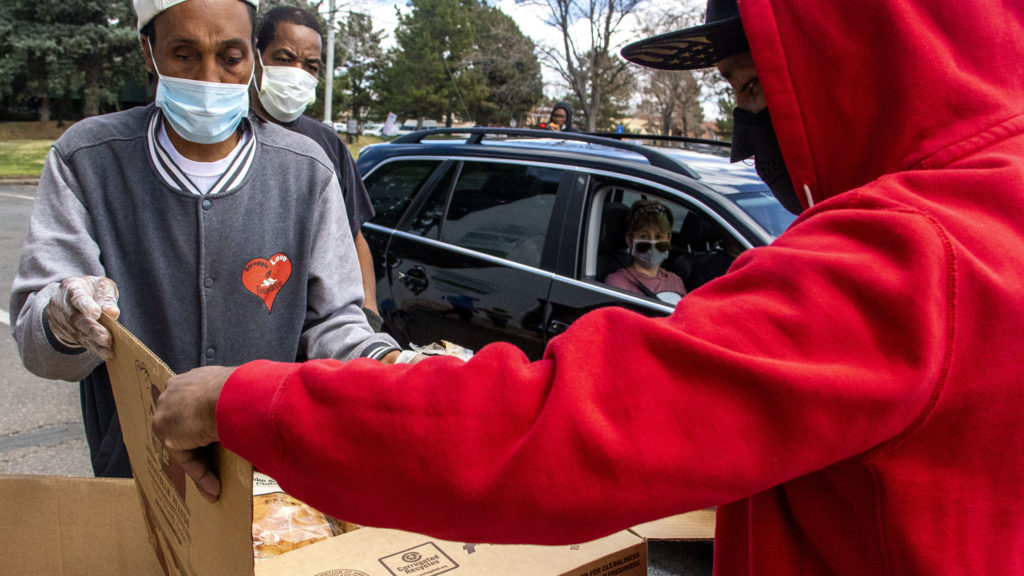 Joel Hodge (left) and Tyrice Catano Sr. unpack boxes of food at the Struggle of Love Foundation's Montbello food pantry. April 24, 2020. (Kevin J. Beaty/Denverite)