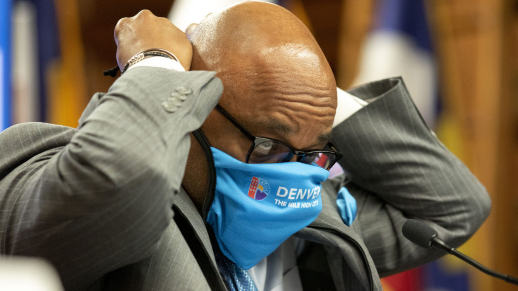 Mayor Michael Hancock ties on his facemask during a COVID-19 update in the City and County Building's Parr-Widener Room. May 5, 2020. (Kevin J. Beaty/Denverite)