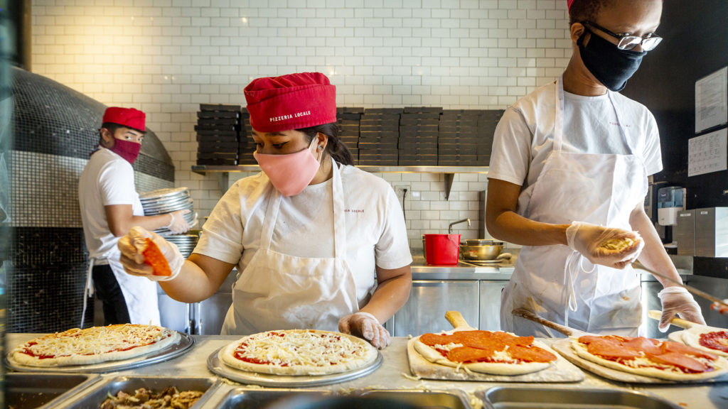 Johann Aneca, Leonela Flores and Kaci Rogers work behind masks at Pizzeria Locale on Broadway. May 7, 2020. (Kevin J. Beaty/Denverite)