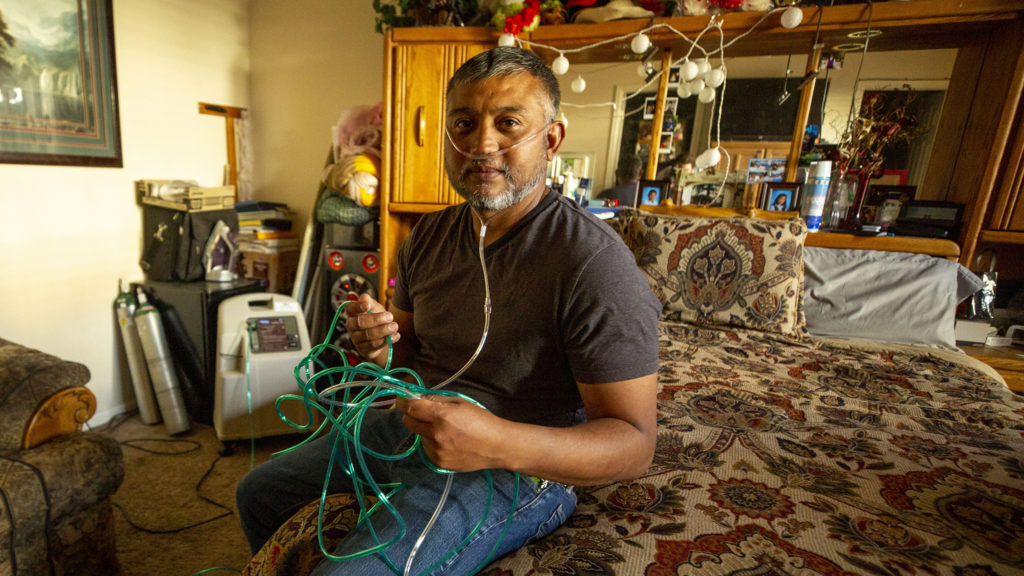 In his bedroom, David Puente wears the oxygen tube he needed while he was recovering from COVID-19. May 13, 2020. (Kevin J. Beaty/Denverite)
