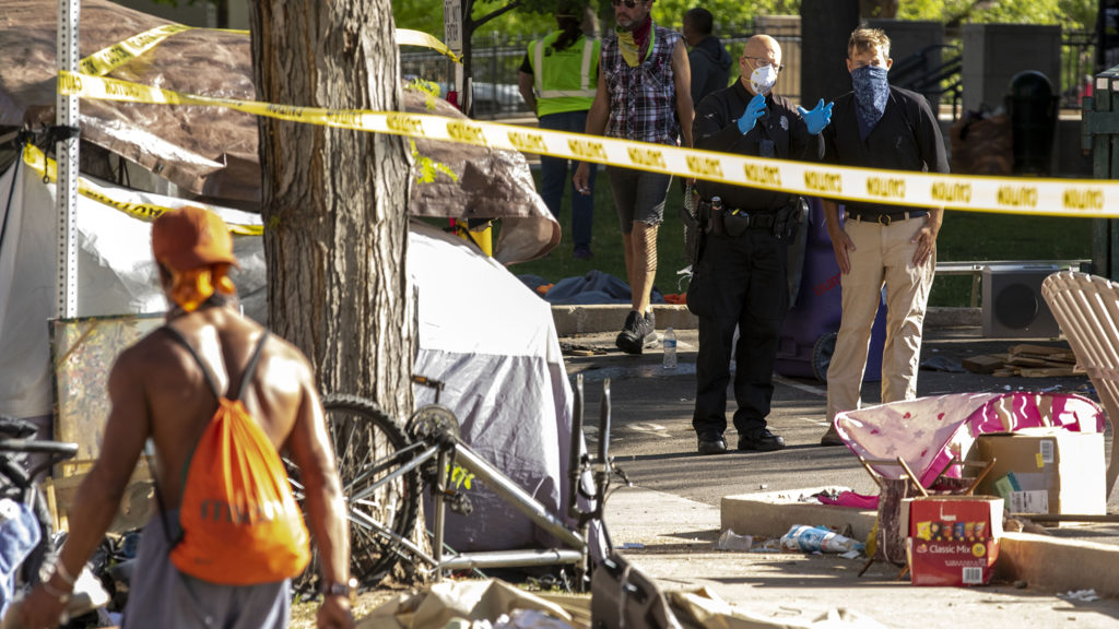 Denver Police Officer Toby Wilson speaks with St. John's Episcopal Cathedral Dean Rev. Richard Lawson as city workers clean up trash and items belonging to people living outside here along the sidewalk. Capitol Hill, May 20, 2020. (Kevin J. Beaty/Denverite)