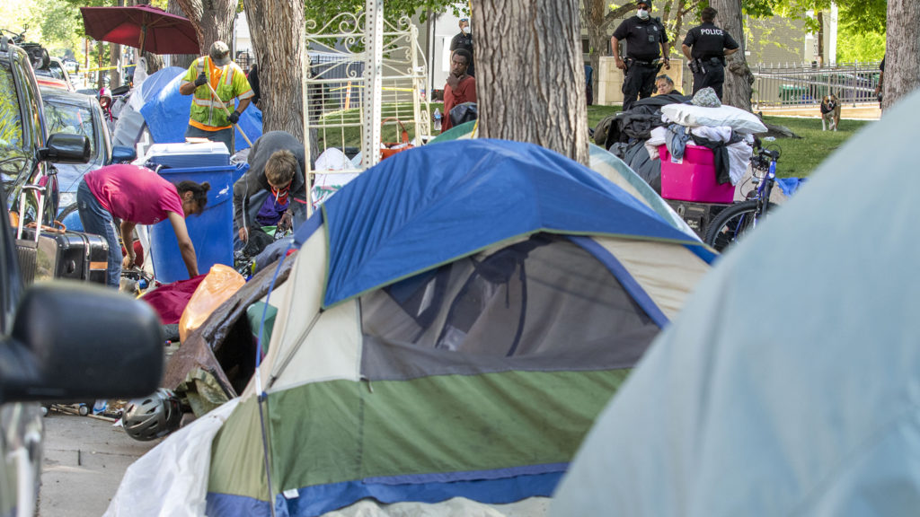 People living outside of St. John's Episcopal Cathedral gather their belongings during a city-run cleanup of the sidewalks here in Capitol Hill. May 20, 2020. (Kevin J. Beaty/Denverite)