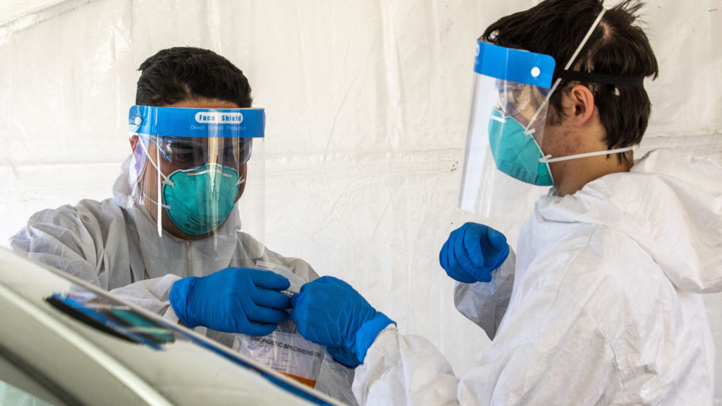 Worers process a COVID-19 swab at new mass testing facility at the Pepsi Center. May 21, 2020. (Kevin J. Beaty/Denverite)
