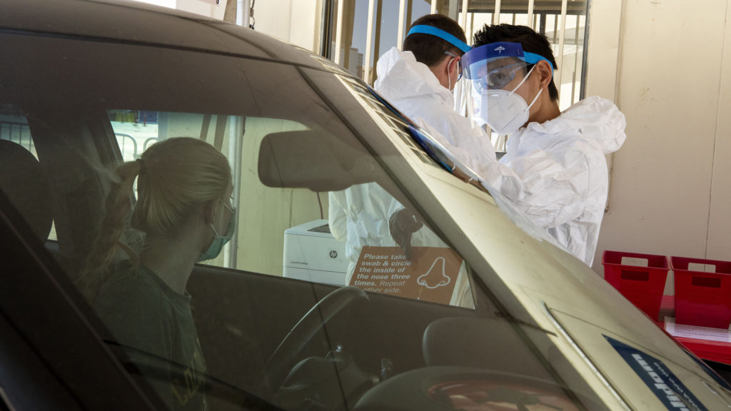 Michael Odom (left) and Takahiro Beachum, employees of Denver Police's crime lab, work a new mass testing facility for COVID-19 at the Pepsi Center. May 21, 2020. (Kevin J. Beaty/Denverite)