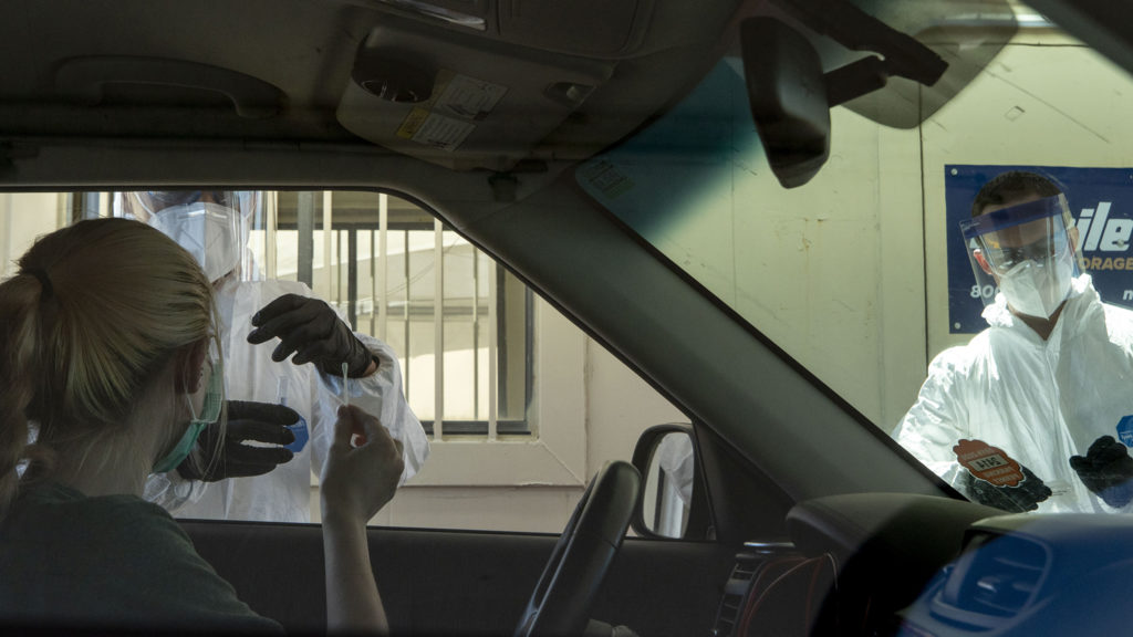 Michael Odom (left) and Takahiro Beachum, employees of Denver Police's crime lab, work a new mass testing facility for COVID-19 at the Pepsi Center. May 21, 2020. (Kevin J. Beaty/Denverite)