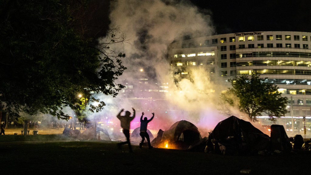 Protesters rush to put out a fire set on an unhoused resident's tent by a Denver Police smoke bomb thrown during a massive reaction to the killing of George Floyd. May 28, 2020. (Kevin J. Beaty/Denverite)