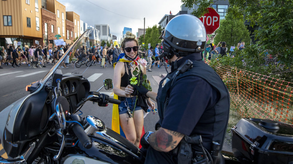 Ana Formoza hands a flower to a Denver Police officer on the sixth day of protests in reaction to the killing of George Floyd by Minneapolis police. June 2, 2020. (Kevin J. Beaty/Denverite)