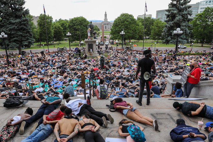 Activist Nate Smith, with a megaphone, looks on as protesters remember George Floyd by laying face down on the ground in front of the State Capitol on June 3, 2020. (Hart Van Denburg/CPR News)