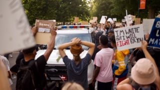 Peaceful protesters surround a Denver Police Department SUV in the middle of Lincoln Street on Monday, June 8, 2020. (Carl Glenn Payne/For Denverite)