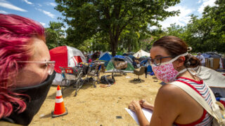 Belle Ruocco (left) and Magdalena Franchois survey an encampment at Lincoln Park, at Lincoln Street and Colfax Avenue, as part of Denver Homeless Out Loud's count of unhoused residents in the city. July 17, 2020.