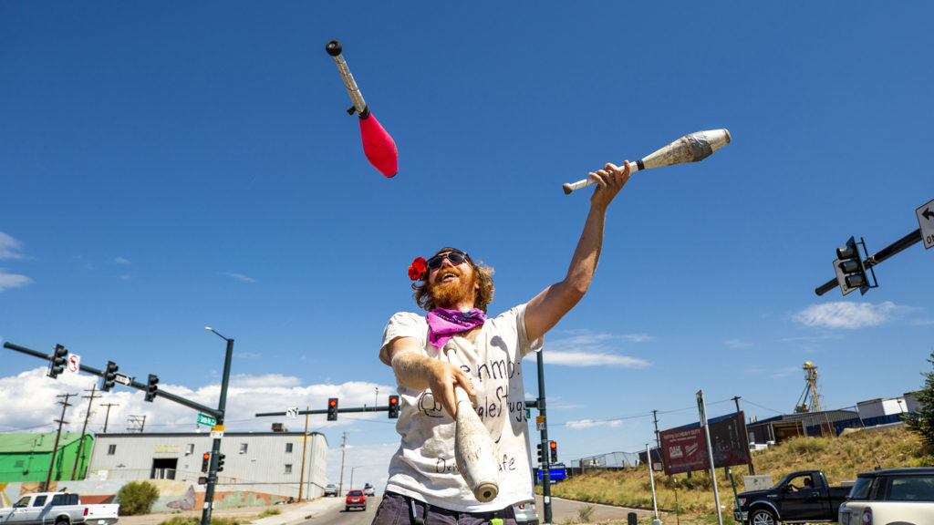Eric Bogel, AKA JuggleStruggle, performs for tips during red lights at a Baker intersection. July 17, 2020.