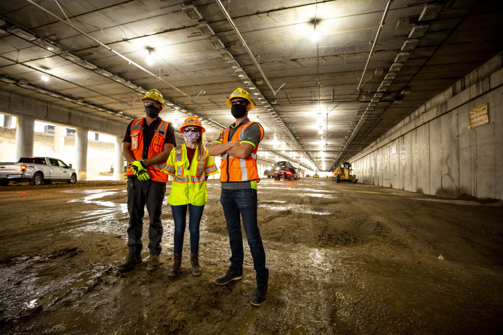 Tanner Peyton (left to right), Stacia Sellers and Matt Sanman stand inside the future, capped section of I-70 that will eventually channel cars below grade through Elyria Swansea. July 28, 2020.