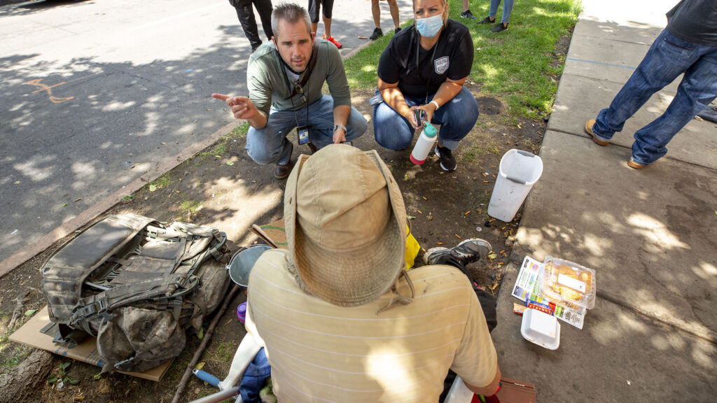 Mental Health Center of Denver workers Chris Richardson and Randi Edwards speak to Charles Gilmore on a sidewalk in North Capitol Hill. July 30, 2020.
