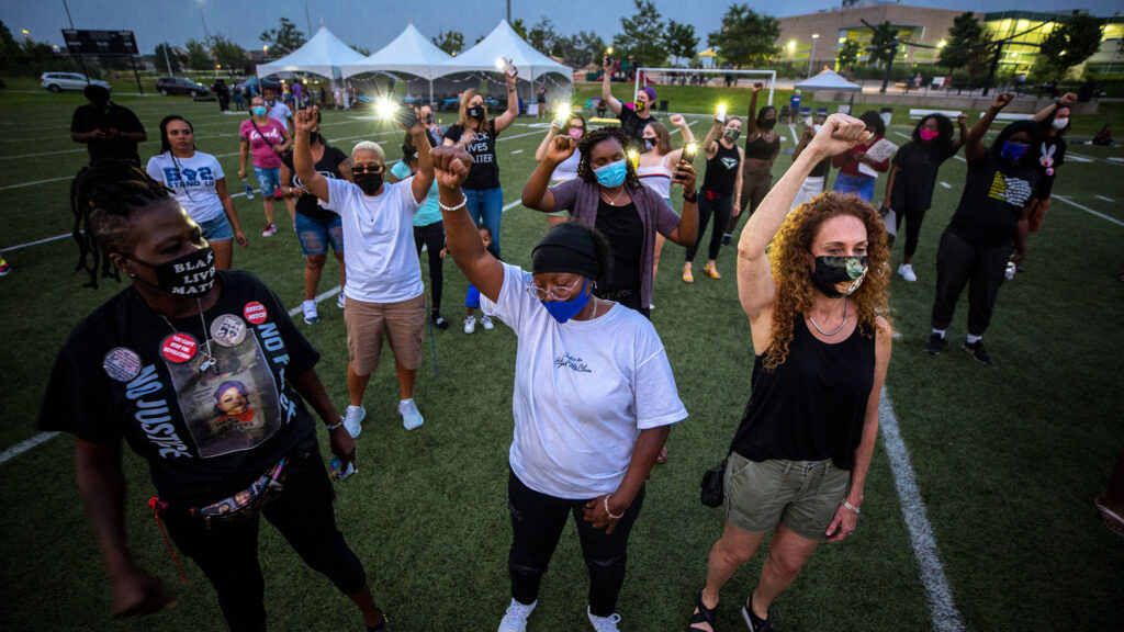 Sheneen McClain holds up a fist during a gathering at the Montbello Rec Center in honor of her son, Elijah. Aug. 23, 2020.