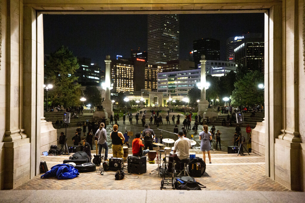 A small group of demonstrators protesting police brutality gather at Civic Center Park as the band Los Mocochetes plays the Greek Amphitheatre. Aug. 28, 2020.