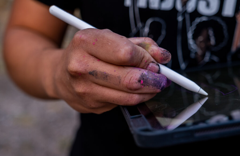 Zeek plans out his mural with a “lazy grid” on his tablet in a River North Art District alleyway on Sept. 17, 2020.