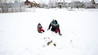 Foster plays in the snow with his au pair, Ambar Tossolini, in GreenWay Park in the Central Park neighborhood. Nov, 24, 2020.