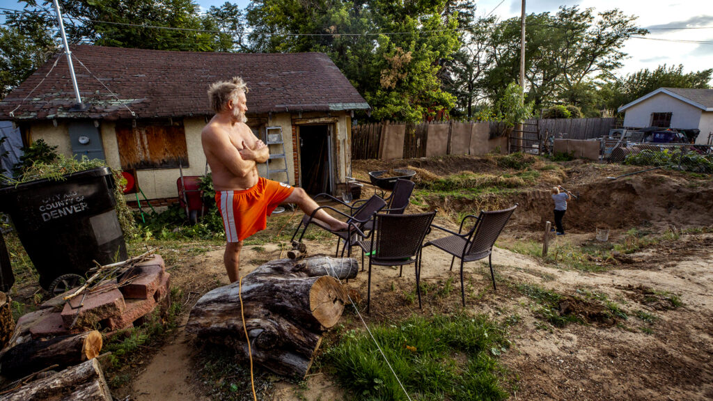 Nick Moses stands before the giant, ongoing, hand-dug pond pit in his back yard off Bruce Randolph Avenue as his son, Quentin, goes to work with a pickaxe. Sept. 11, 2020.