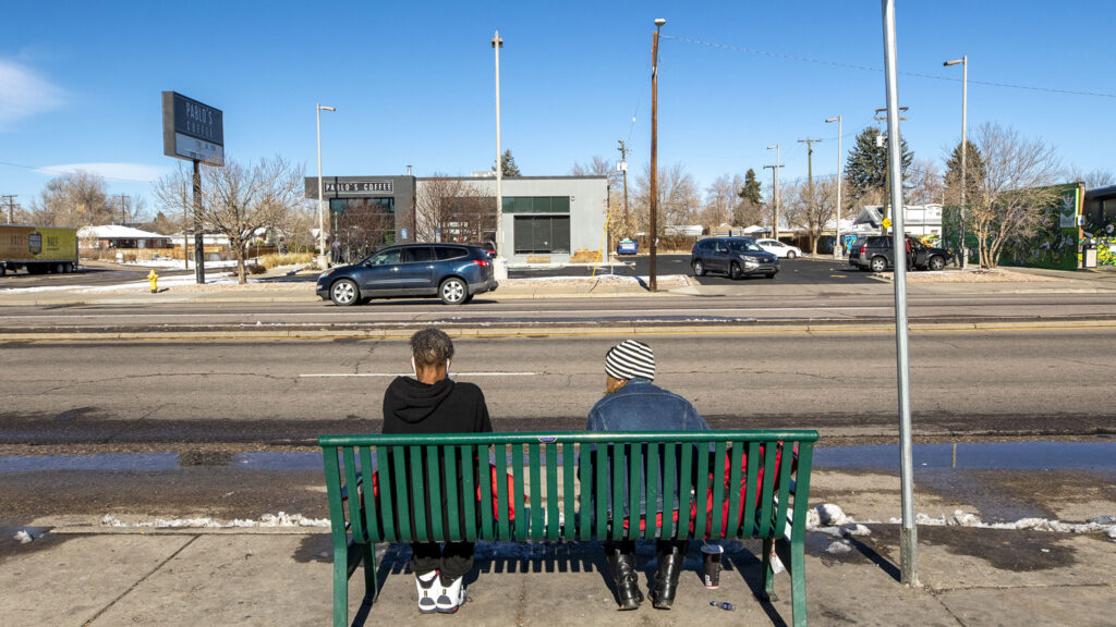 Kristy Jo Gower, right, waits for a bus with someone she just met on East Colfax Avenue, Nov. 25, 2020. Gower said she'd spend a million dollars on helping people experiencing homelessness, like herself. "They need help to stand up," she said. "They don't need a kick in the teeth."