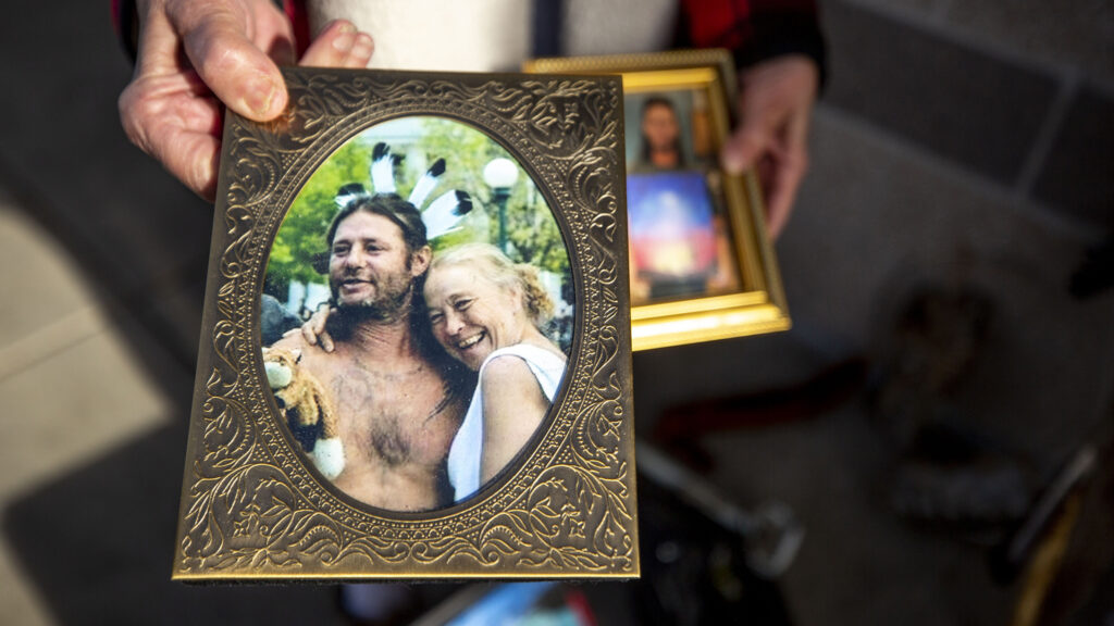 Stacy Neill holds a photo of her and her late partner, Todd Ham, in front of The Fourth Quarter apartments in Whittier. Dec. 17, 2020.
