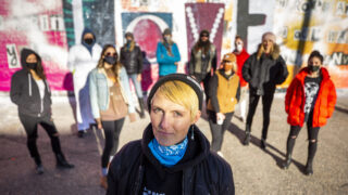 Surrounded by friends and supporters, Robyn Frances stands in front of a mural dedicated to the women of Denver's art scene, off Larimer Street in Five Points' RiNo district, that was recently defaced. Dec. 19, 2020.