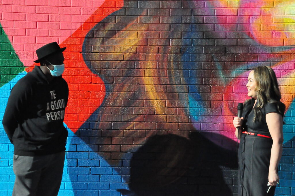 Thomas Evans stands with Nga Vuong-Sandoval, a refugee who fled Vietnam with her family as a child — and who now advocates for the rights of other refugees and immigrants — after a dedication of the mural depicting her on Sunday, December 6, 2020.