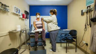 Medical assistant Yasmin Tellez prepares to give Maria Chacon the first of two COVID-19 vaccinations at Globeville's Clinica Tepeyac. Jan. 26, 2021.