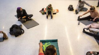A small group of protesters do yoga during a sit-in against new rules barring sleeping and sitting on the ground inside Union Station's bus terminal. Feb. 3, 2021.