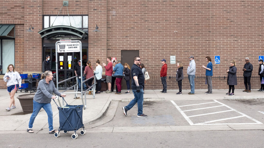 A line at Argonaut Wine and Liquors in Capitol Hill appeared soon after Mayor Michael Hancock announced a "shelter in place" order and quickly stretched around the building. March 23, 2020. (Kevin J. Beaty/Denverite)