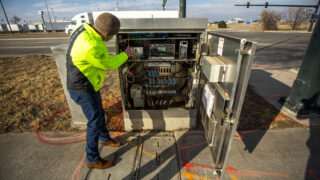 Michael Finochio, transportation engineer with the Denver Department of Transportation and Infrastructure, shows off the guts of a stoplight array that contains technology to talk to connected vehicles. Feb. 11, 2021.