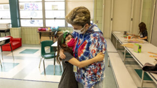 Rylan, a second-grader, hugs Carson Elementary Discovery Link leader Jennifer Piel before regular classes begin on March 17, 2021.