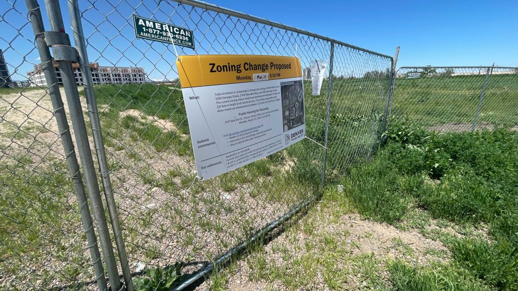 A fence surrounding 2650 Arkins Ct. with a sign on its proposed rezoning on Monday, May 24, in the Five Points neighborhood. (Esteban L. Hernandez/Denverite)