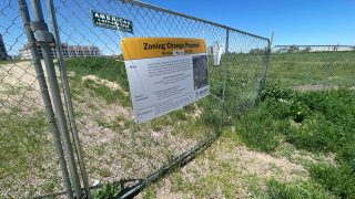 A fence surrounding 2650 Arkins Ct. with a sign on its proposed rezoning on Monday, May 24, in the Five Points neighborhood. (Esteban L. Hernandez/Denverite)