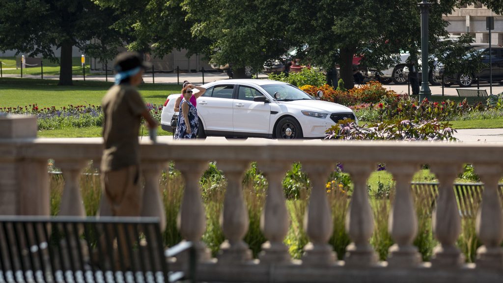 A Denver Police officer sits in a cruiser parked conspicuously in the middle of Civic Center Park. July 10, 2021.