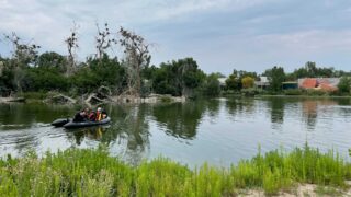 A raft full of divers from the Denver Fire Department scans Duck Lake at City Park on Aug. 3, 2021. Authorities say they were searching for a person who witnesses said rode a bike into the water and did not resurface.