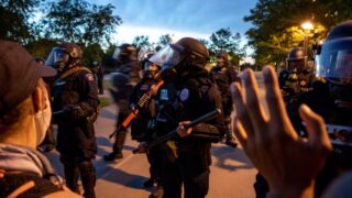 Aurora Police officers push protesters and musicians away from the municipal complex's lawn after a series of rallies and protests demanding justice for Elijah McClain. June 27, 2020.