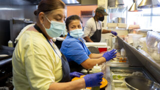 Maria Sanchez (left) and Marta Uroza run the line inside Comal Kitchen at Globeville's Taxi campus. Oct. 13, 2021.