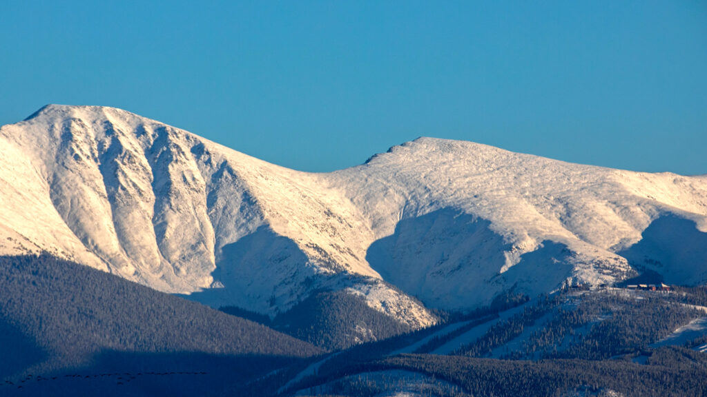 West facing slopes covered in October snow on the Continental Divide as the sun sets, with Winter Park in the foreground at right, Tuesday evening, Oct. 27, 2020.