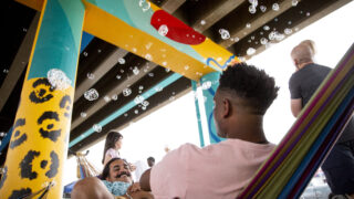Sandeep Sapra and Jamonie Shorts hang out on a hammock surrounded by bubbles at Sun Valley Rising's Viaduct Night Market beneath Colfax Avenue. May 14, 2022.