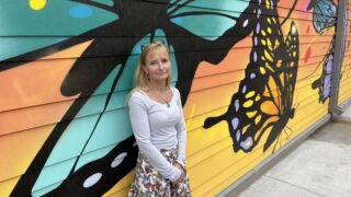 Melissa Diaz stands in front of a mural in the courtyard of the Viña Apartments in Elyria-Swansea. May 4, 2022.