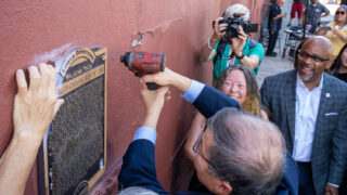 William Wei, board member of the Colorado Asian Pacific Union, removes a plaque from a LoDo neighborhood wall on 20th Street across from Coors Field, on Monday, August 8, 2022. The marker mischaracterized a brutal 1880 assault by whites against Chinese immigrants living and working in Denver as a “Chinese Riot.” The move, led by Denver Mayor Michael Hancock’s office, comes following a formal apology earlier this year.