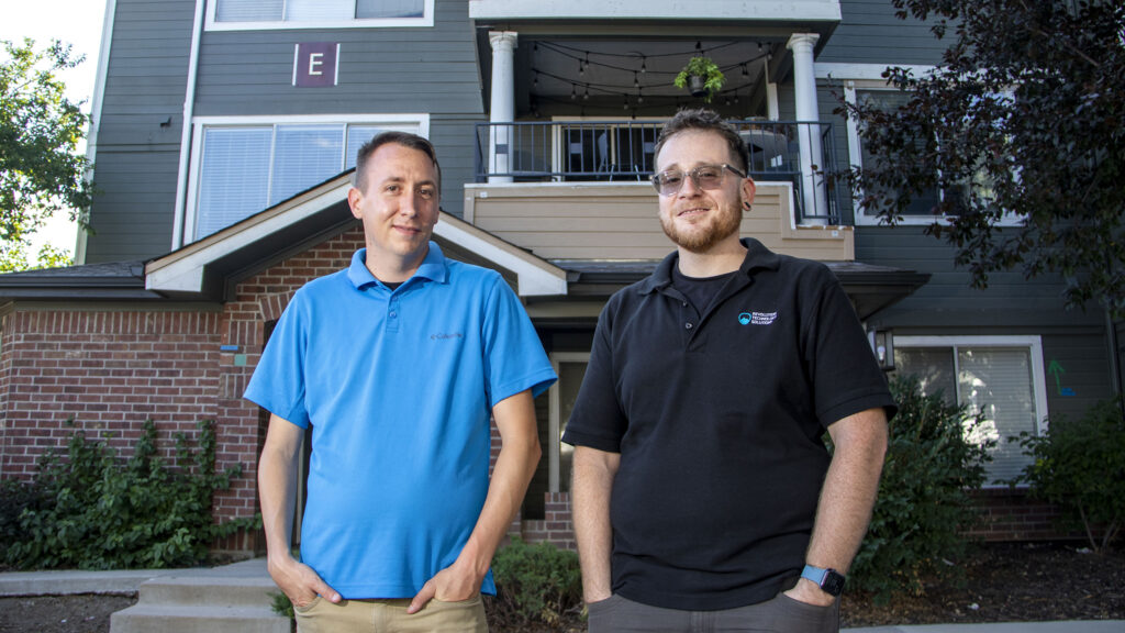 William Paul Colgan and Victor Sobrado stand in front of their apartment in Tava Waters, in Denver's Lowry neighborhood. Aug. 10, 2022.