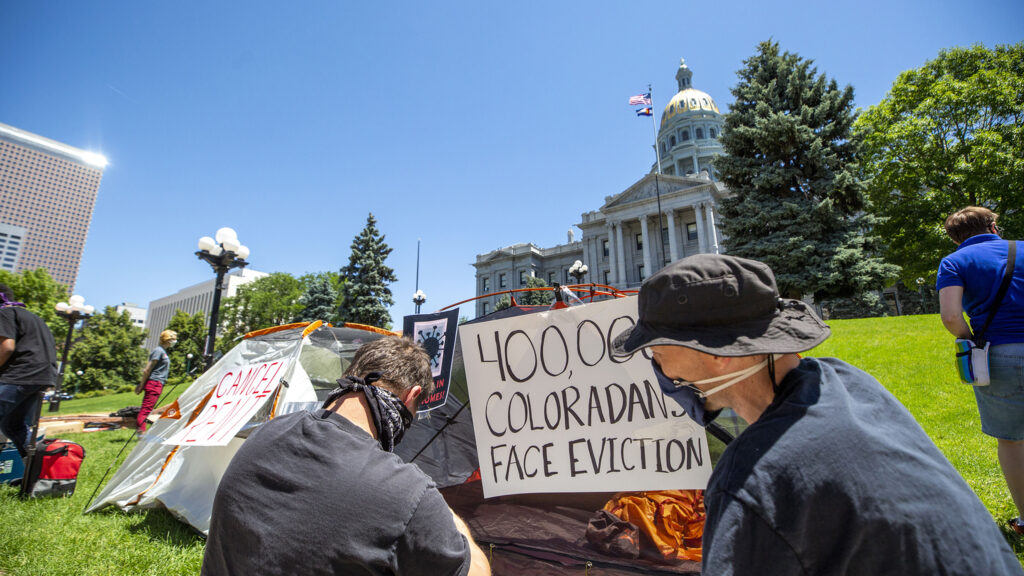 Kevin Breidenbach y Luke Wierman colocan carteles en las tiendas de campaña mientras los Socialistas Democráticos de América en Denver protestan contra el alquiler y los desalojos conforme la economía sigue sufriendo durante la pandemia. 1 de julio de 2020.