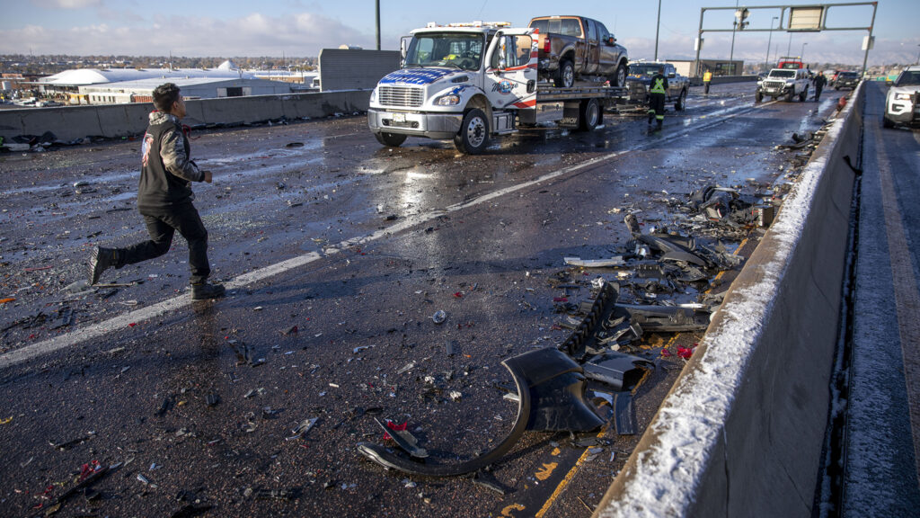 A man runs across the W. 6th Ave. overpass as a tow truck prepares to move a wrecked car on Nov. 4, 2022.