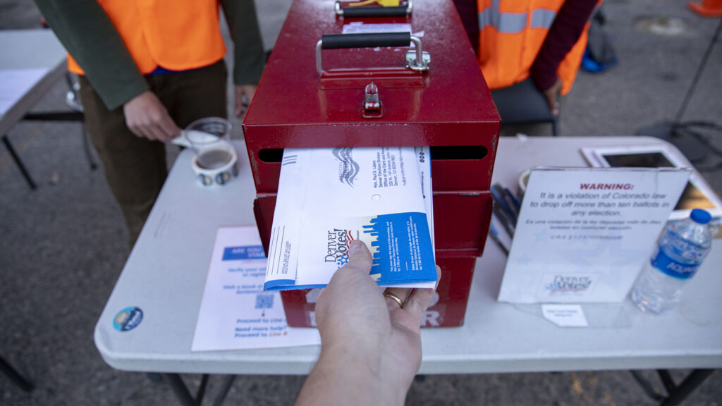 A photographer drops off his ballot at a mobile polling center in downtown Denver on election day. Nov. 8, 2022.