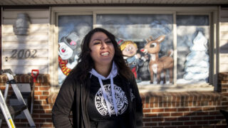 Window artist Gina Trujillo stands in front of a new Christmas scene painted on a Harvey Park home. Nov. 18, 2022.