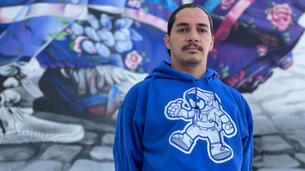 Bimmer Torres stands in front of his mural "Mitotli" on the silos of Ardent Mills Flour Refinery.