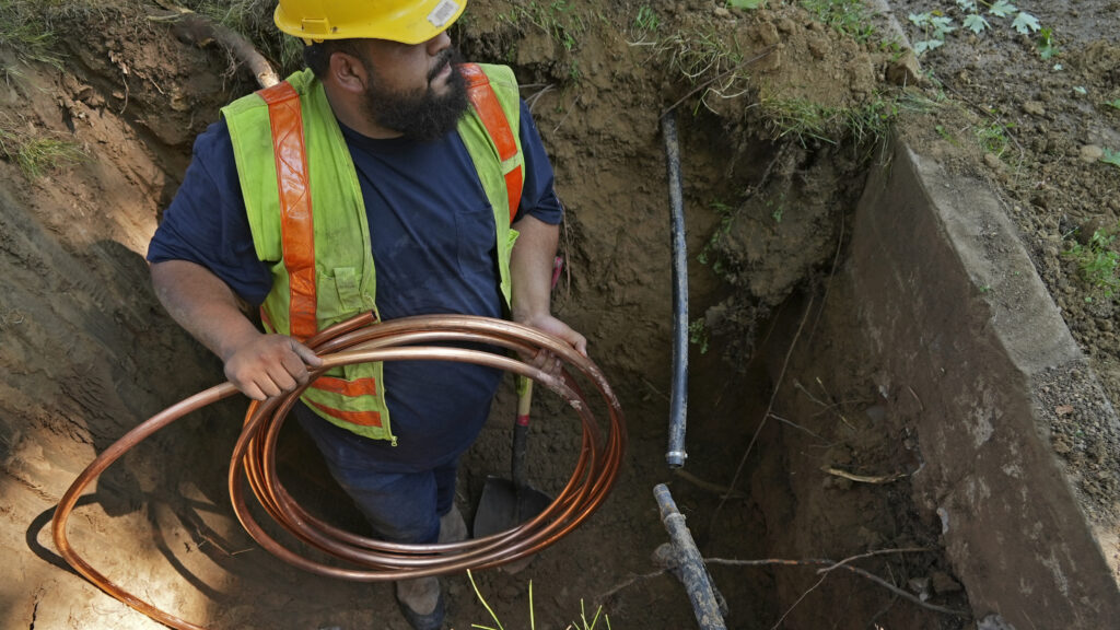 A worker with Denver Water prepares to pass a new copper water service line from a residential water meter to the water main June 17, 2021, in Denver.