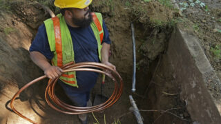 A worker with Denver Water prepares to pass a new copper water service line from a residential water meter to the water main June 17, 2021, in Denver.